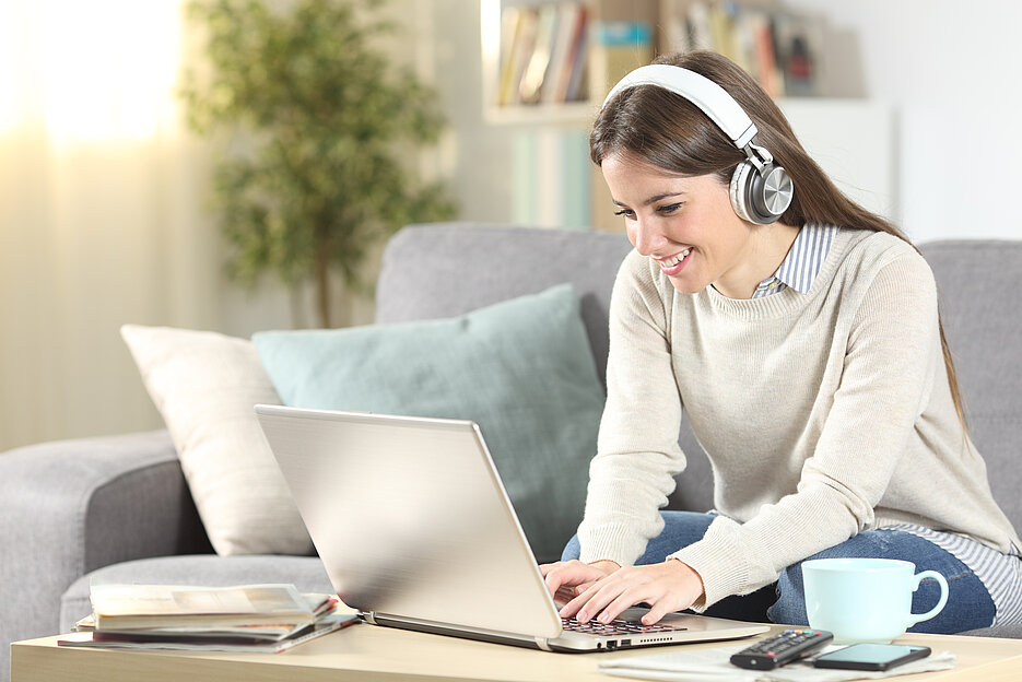 Happy girl e-learning with laptop and headphones